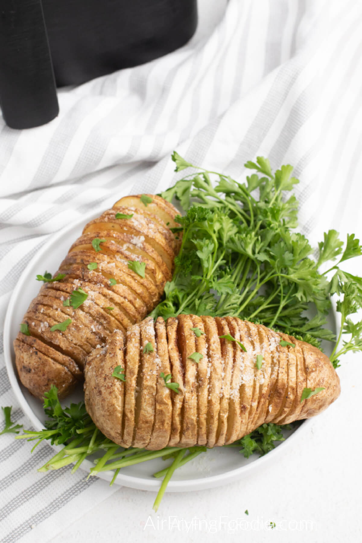 Air fried Hasselback potatoes cooked and served on a white plate. 