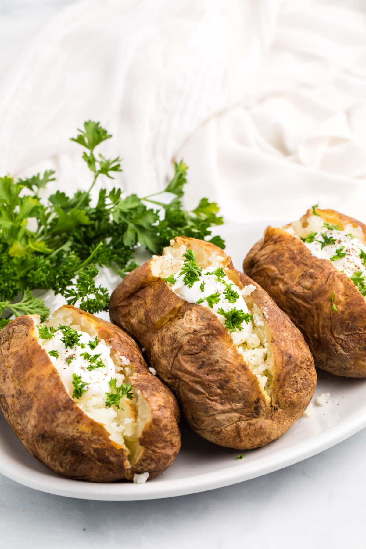 baked potatoes sliced open and topped with sour cream and fresh parsley.