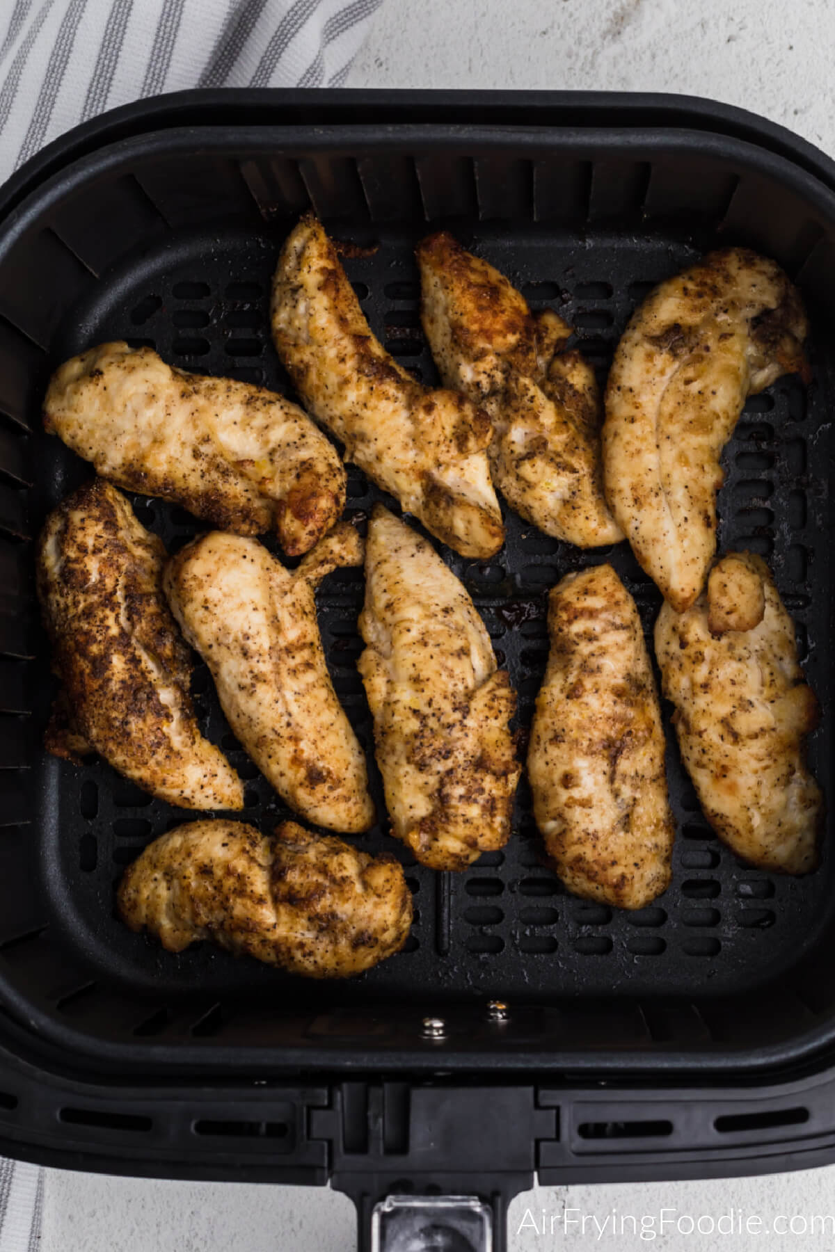Chicken tenders in the air fryer basket in a single layer, ready to be reheated. 