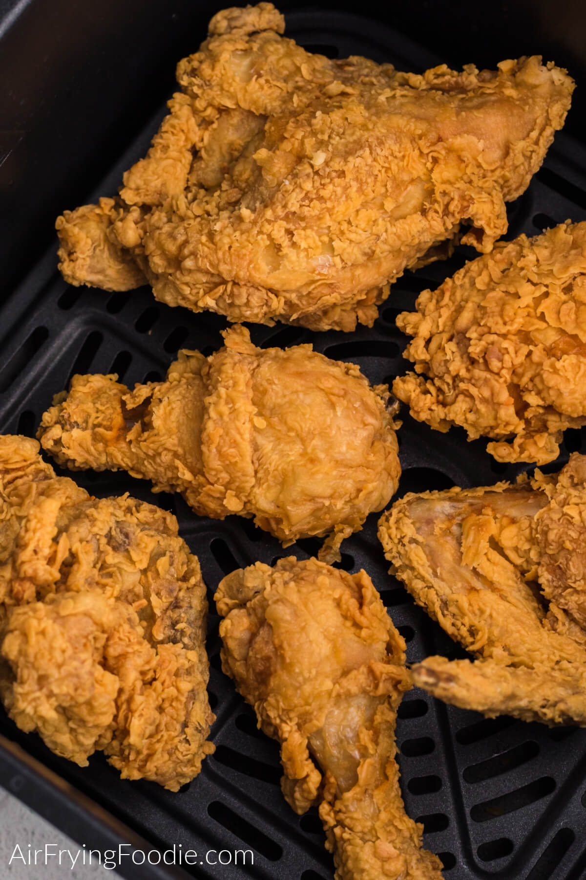 Close up photo of fried chicken in air fryer basket, ready to serve.