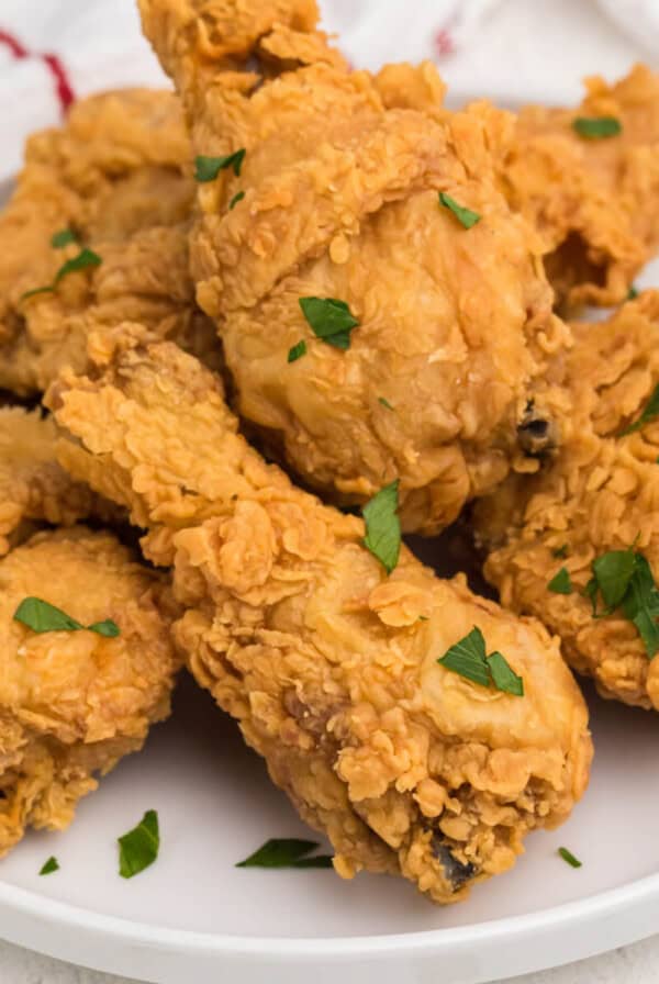 Fried chicken on a white plate that was reheated in the air fryer and garnished with fresh parsley.