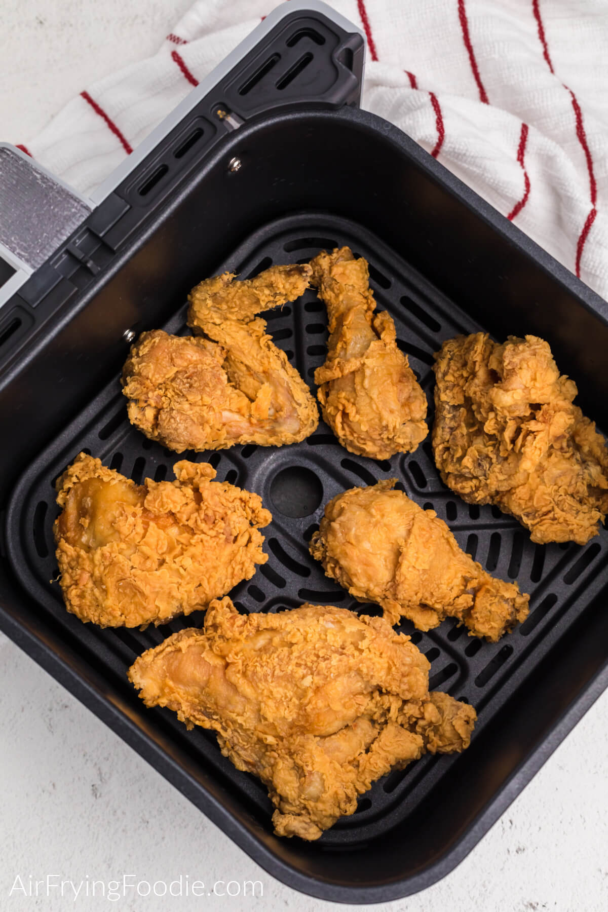 Fried chicken in air fryer basket, spaced apart evenly for air circulation and even cooking. 