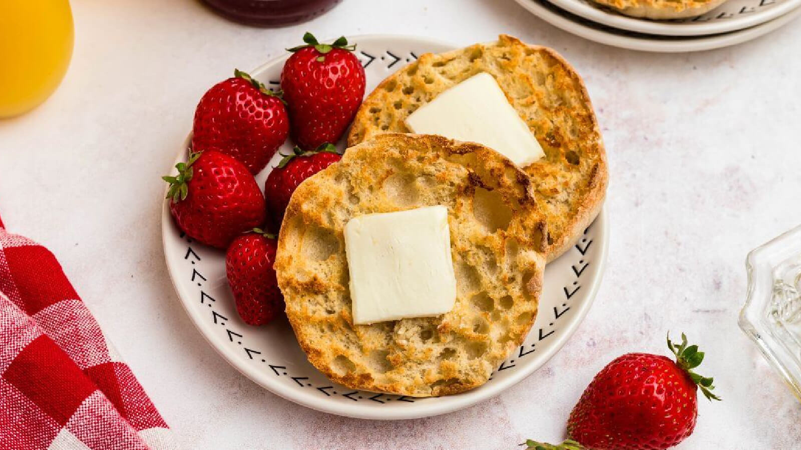 english muffins made in the air fryer on a plate with a pat of butter and strawberries. 