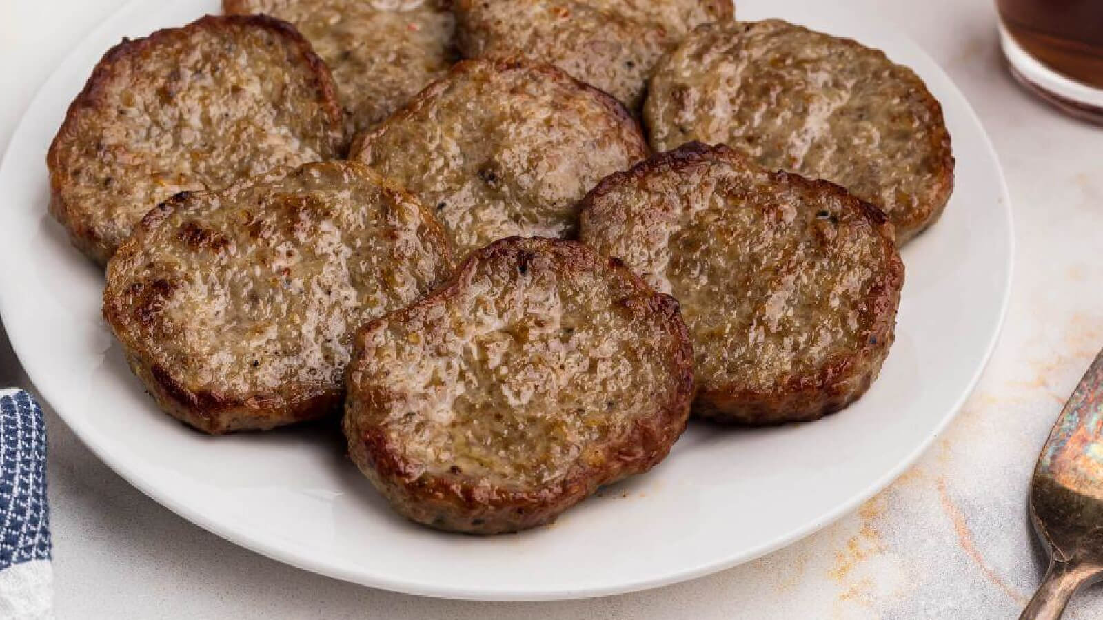 sausage patties made in the air fryer and served on a white plate.