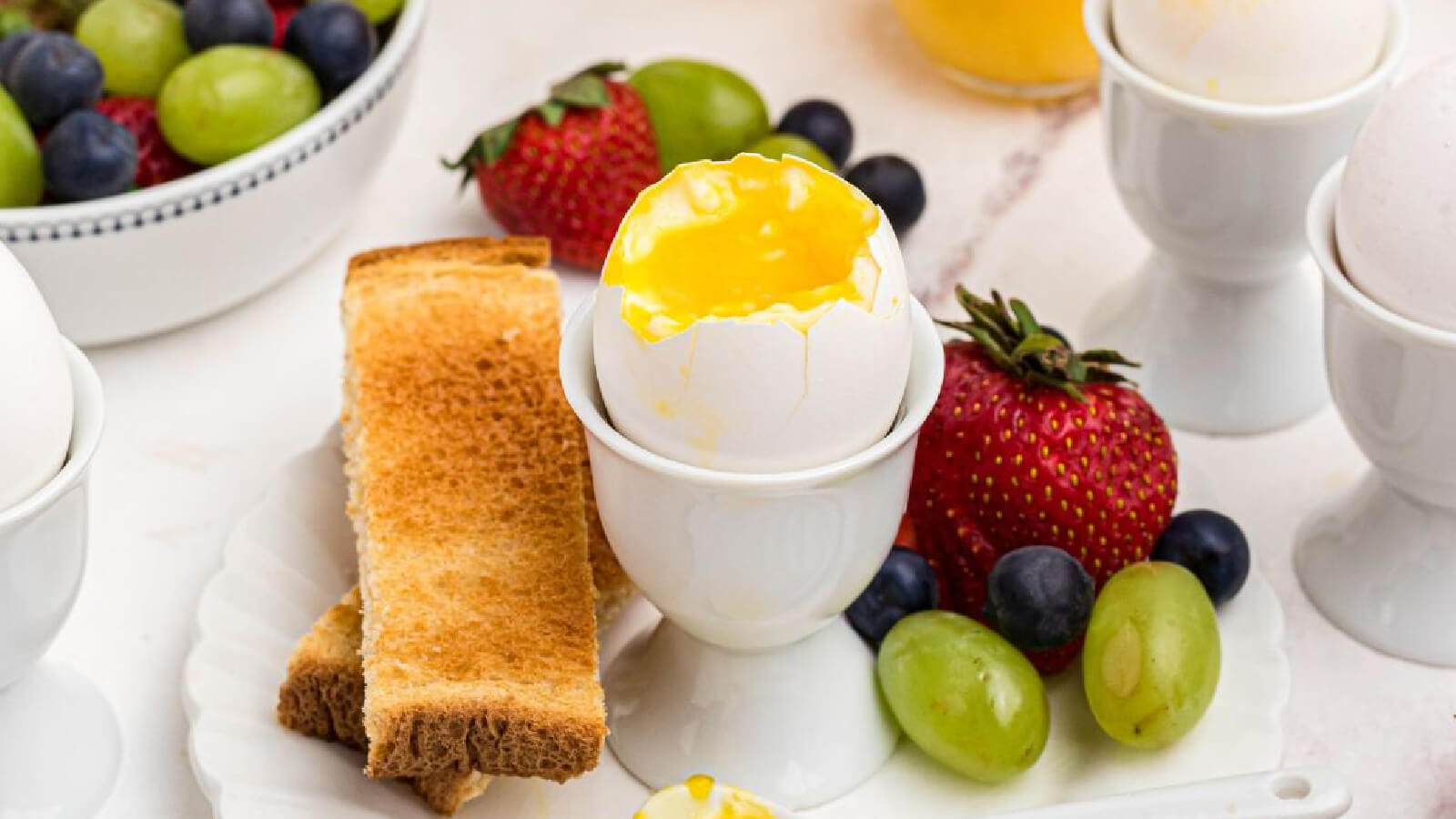 Air fryer soft boiled egg cracked open and half eaten surrounded by fruit and toast.