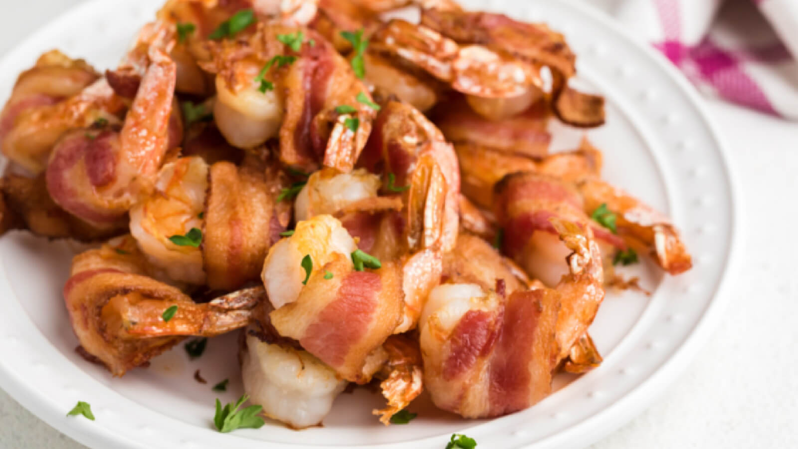 bacon wrapped shrimp on a white plate, ready to serv.e
