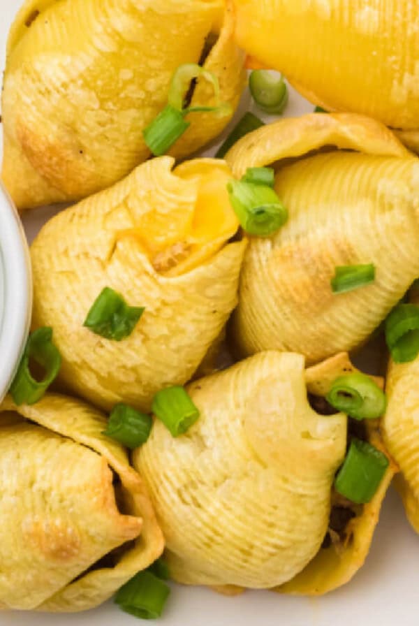 Taco stuffed shells on a serving tray with a side of guacamole in a small bowl.