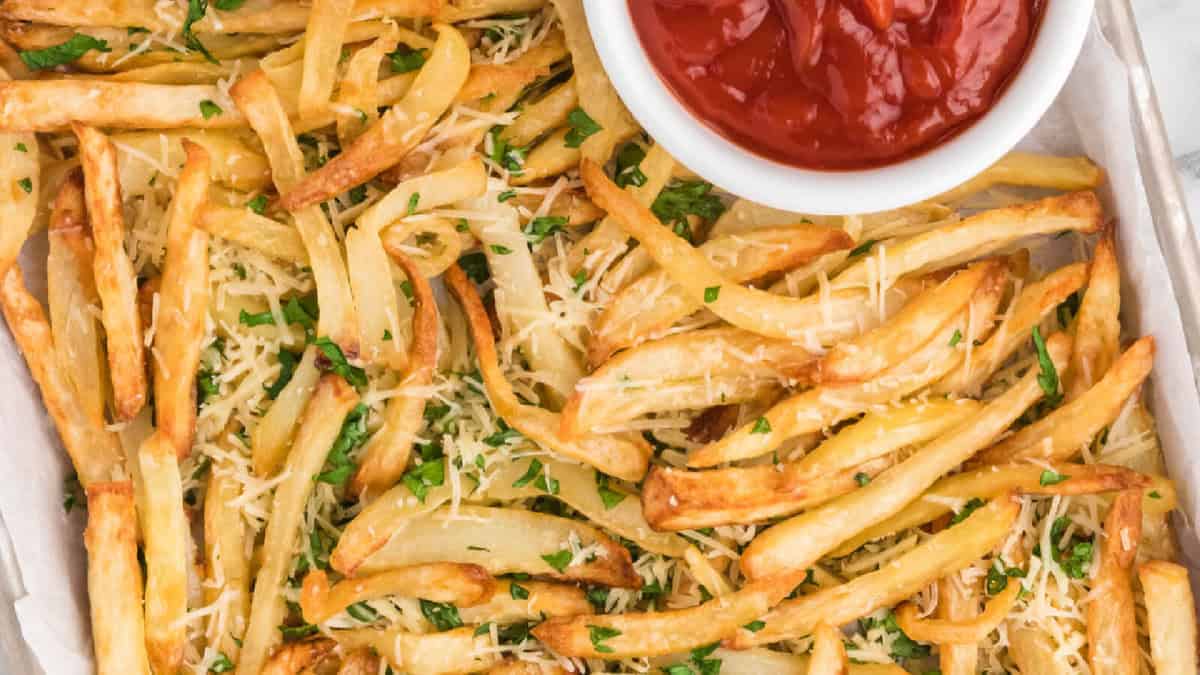 Truffle fries on a tray with a side of ketchup in a white bowl.