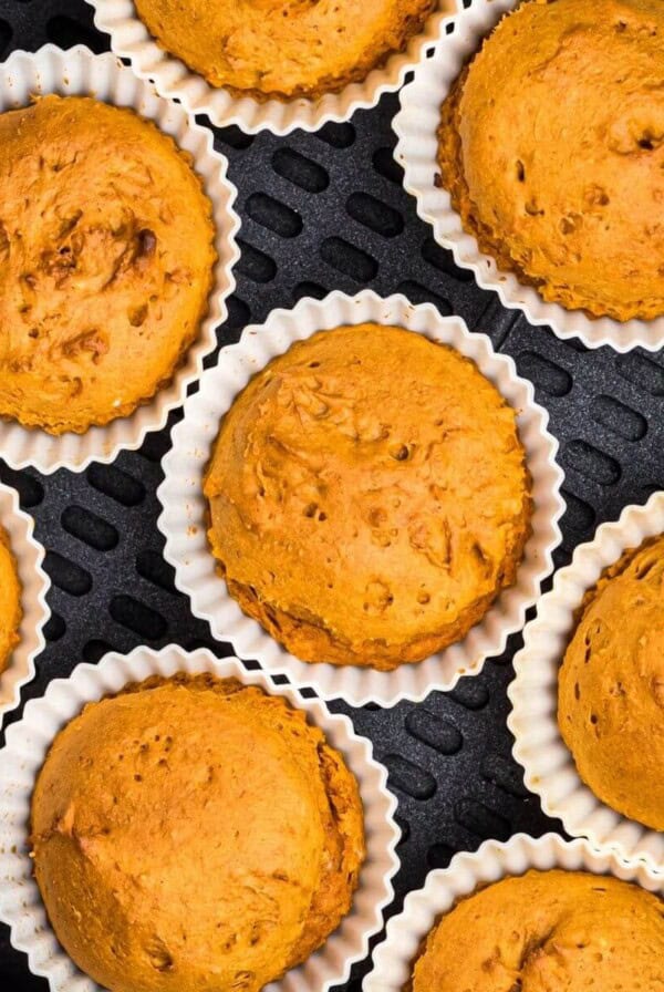 Moist orange pumpkin muffins in silicone liners in the air fryer basket.