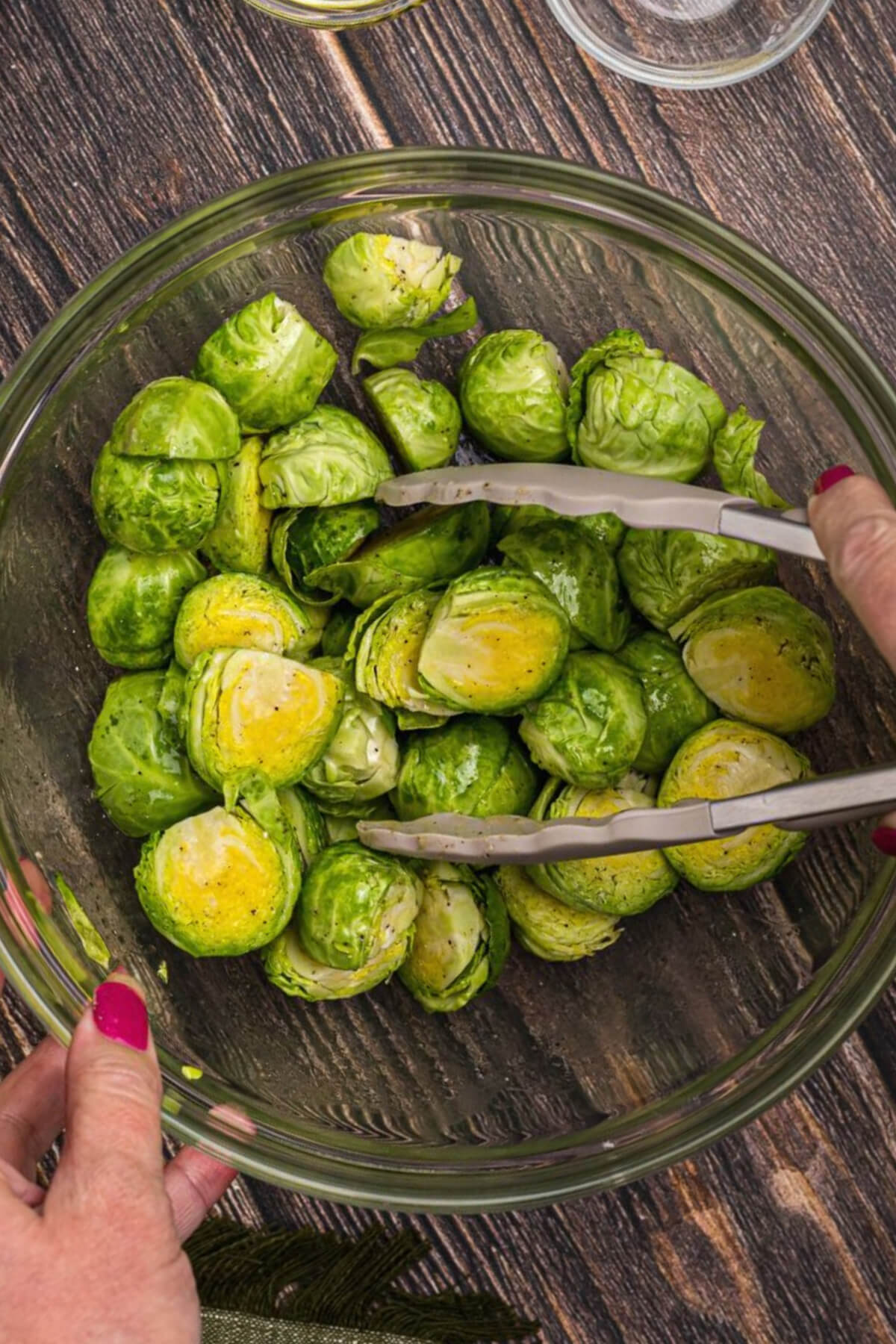 brussels sprouts in a bowl being tossed and coated with olive oil and seasonings. 