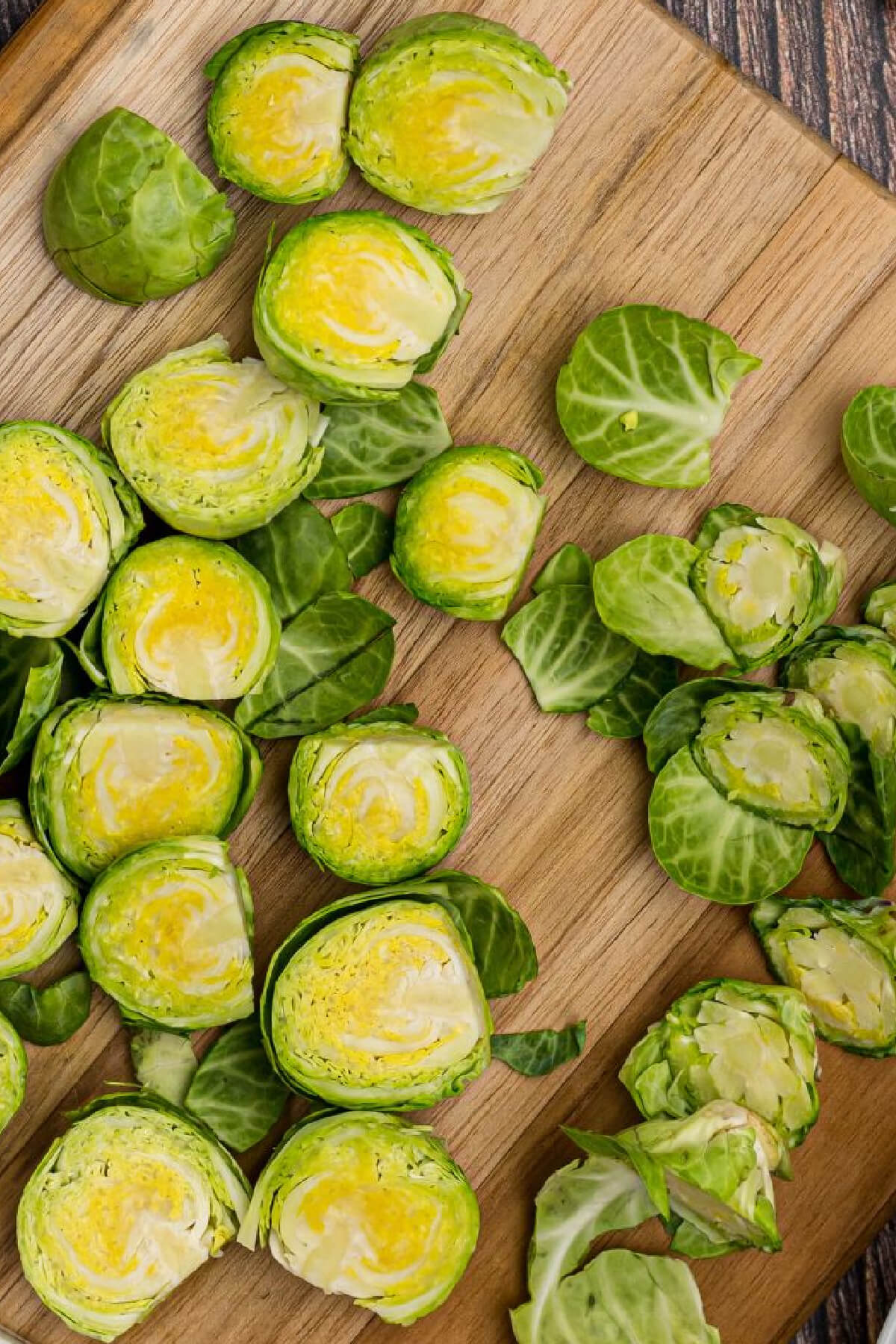 Brussels sprouts on a cutting board sliced in half and with leaves removed. 