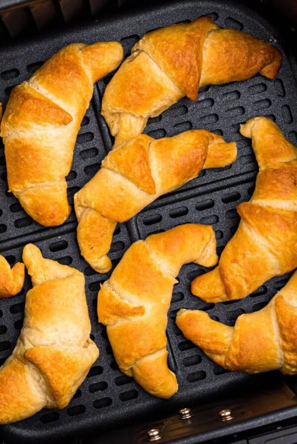 Golden crescent rolls in the air fryer basket after being cooked.