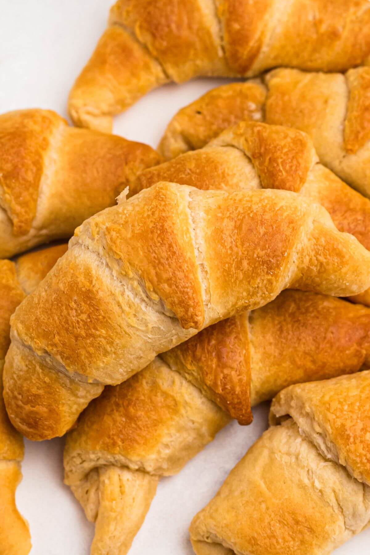 Golden flaky crescent rolls stacked on a marble table. 