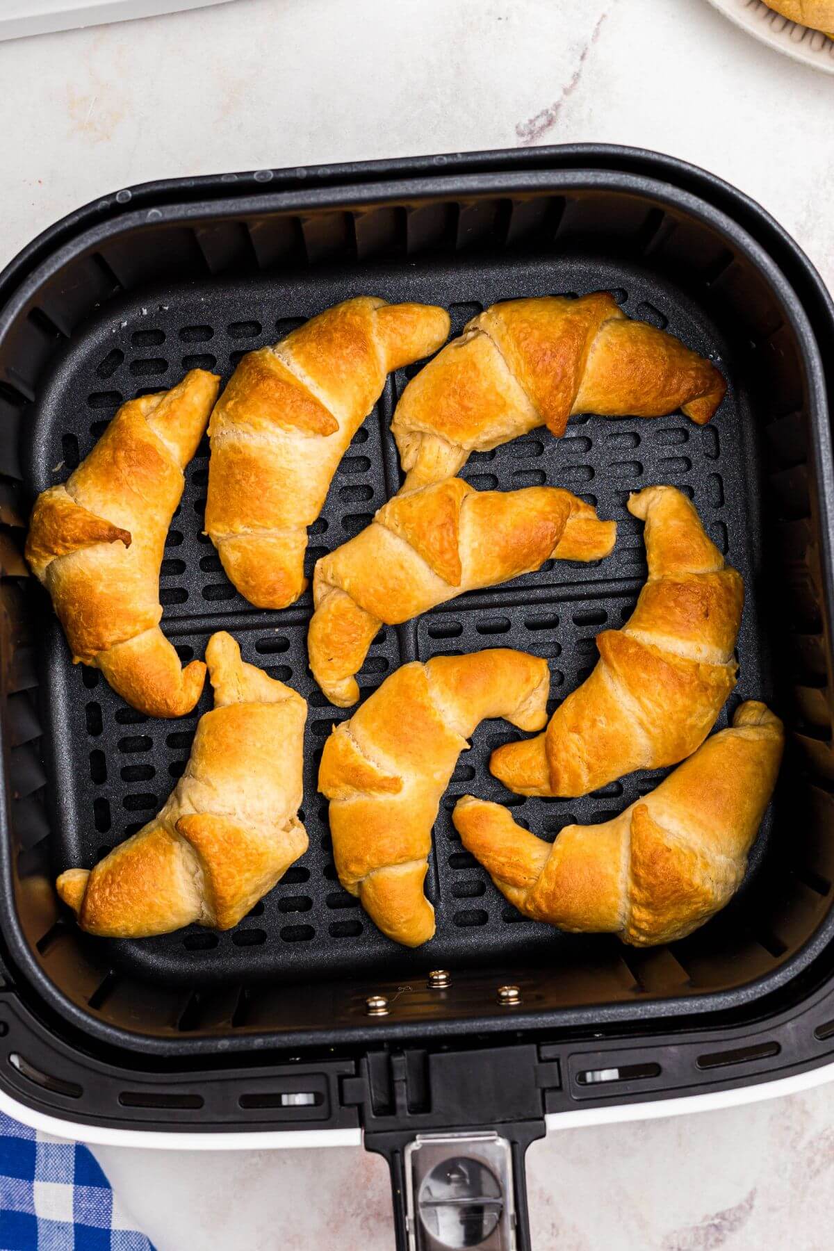 Golden crescent rolls in the air fryer basket after being cooked. 