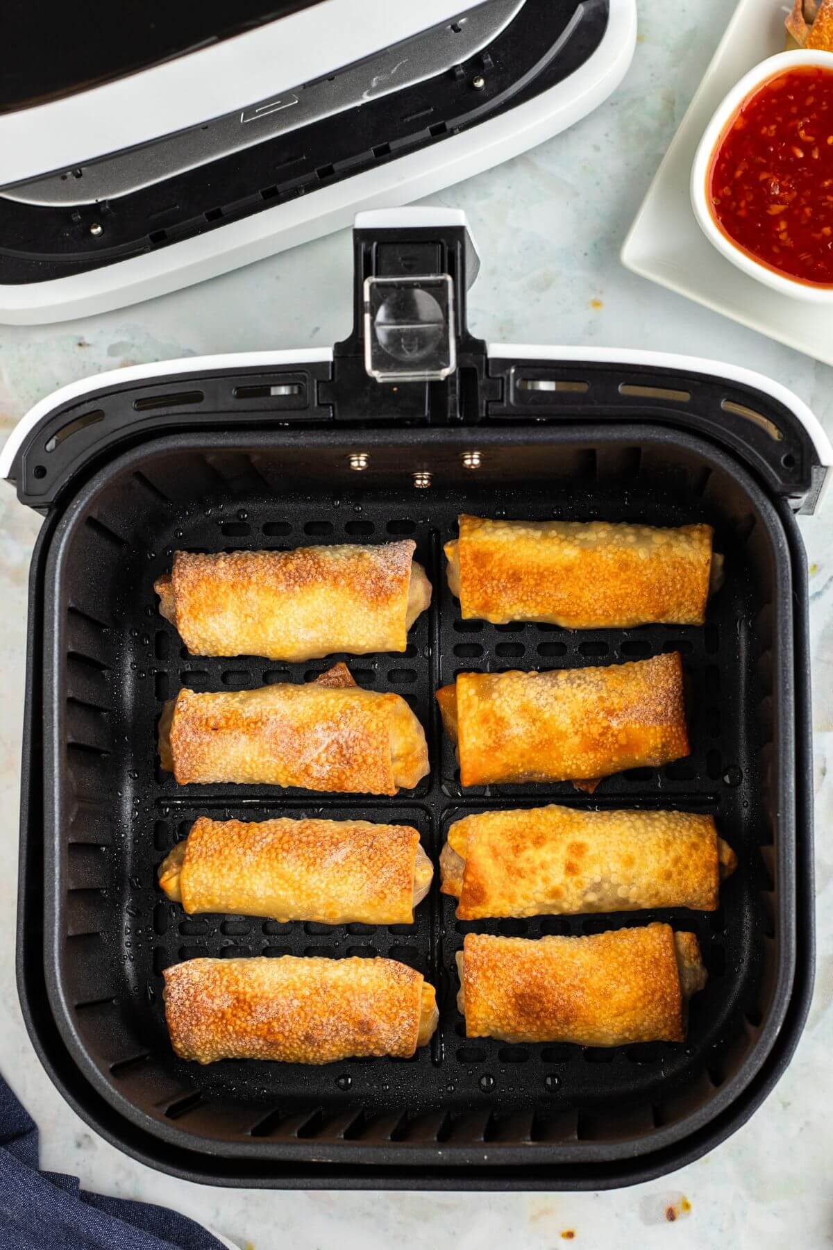 Golden egg rolls in the air fryer basket after being cooked. 