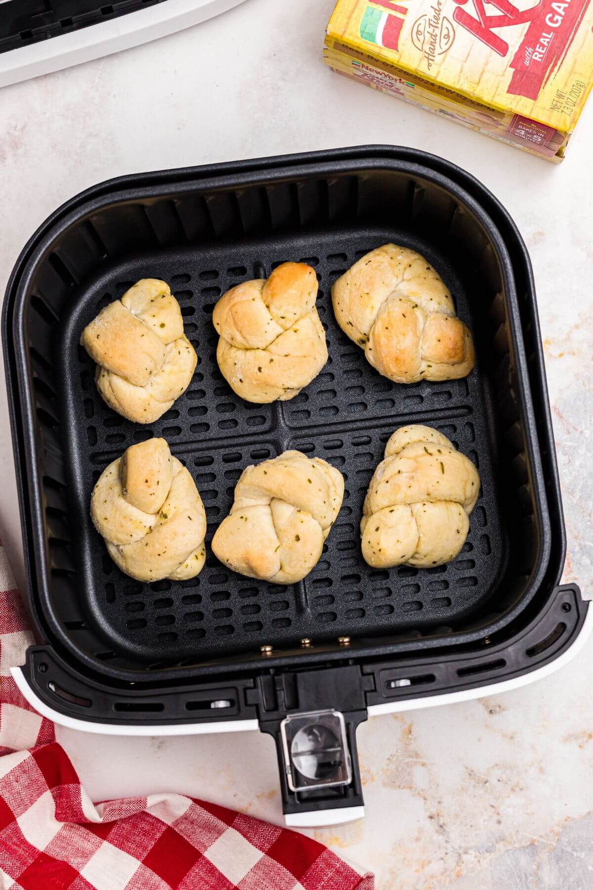 Frozen garlic knots in an air fryer basket before being cooked. 