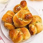 Golden garlic knots on a white plate after being air fried, on a marble table.