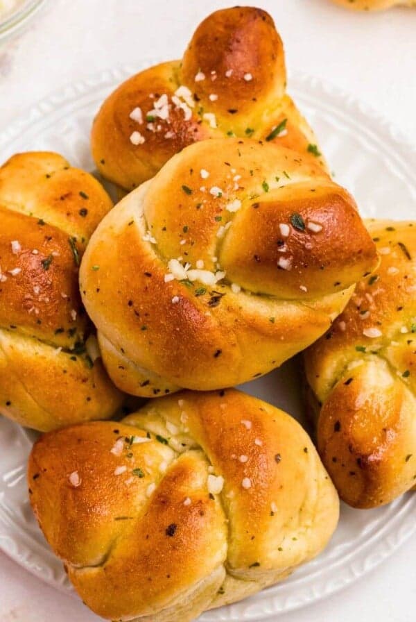 Golden garlic knots on a white plate after being air fried, on a marble table.