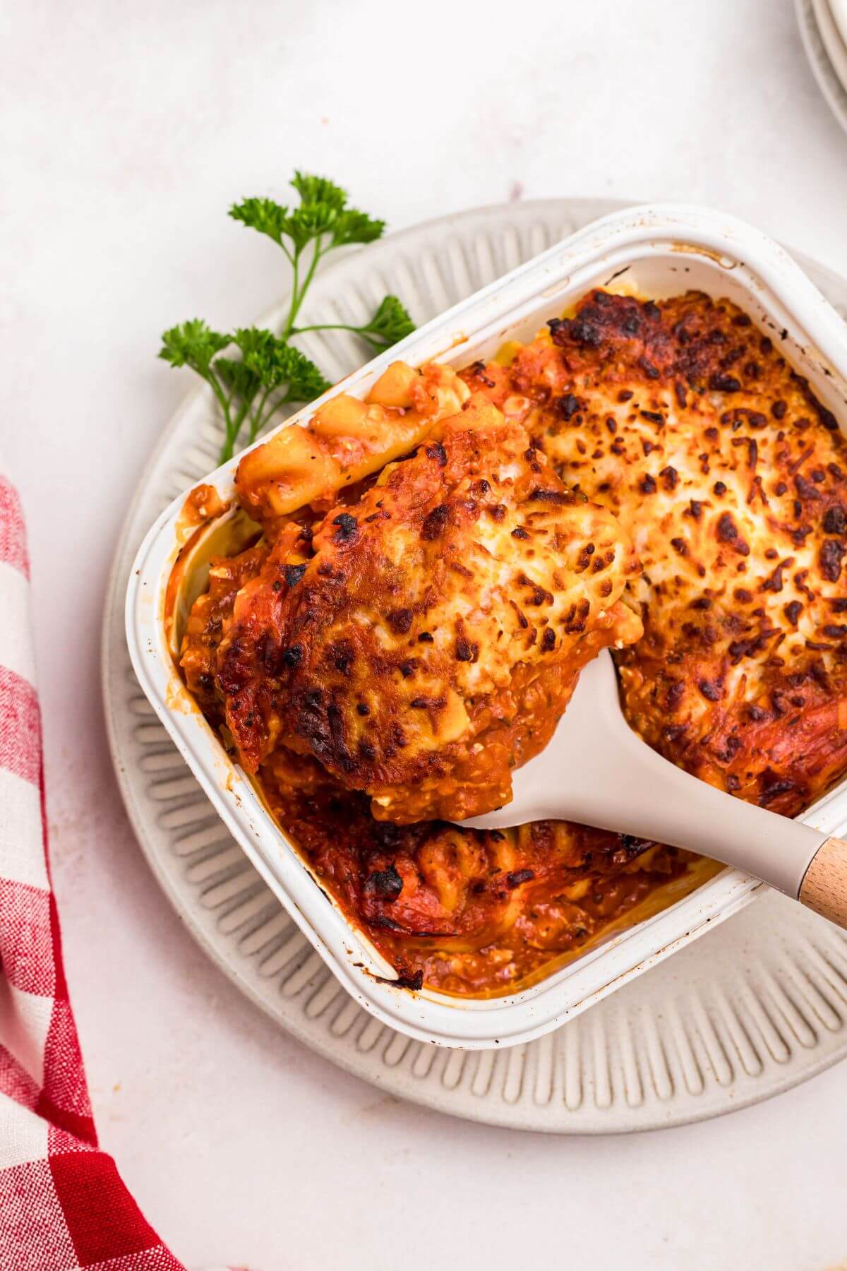 Juicy lasagna in a small tray being lifted out of the container with a spatula. 