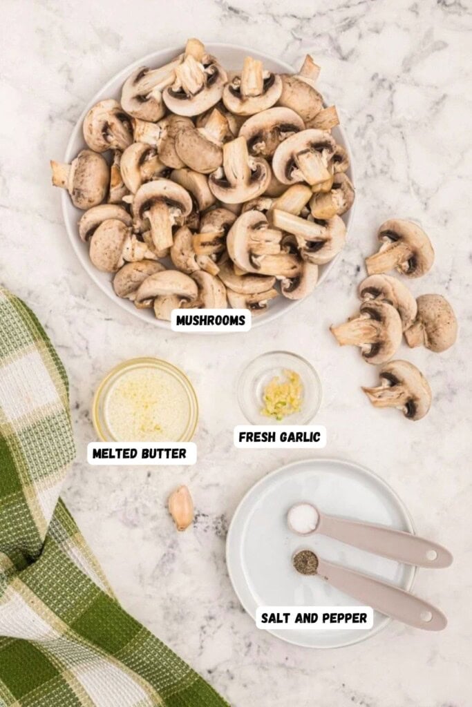 Ingredients needed to make mushrooms. Butter, garlic, salt and pepper, measured into small bowls on a white marble table. 