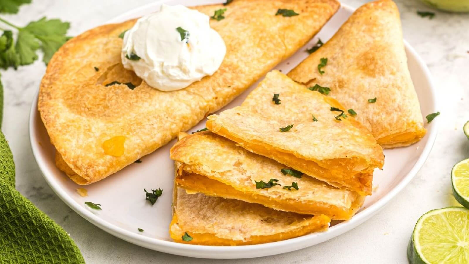 Quesadillas on a white plate with a dollup of sour cream on them.