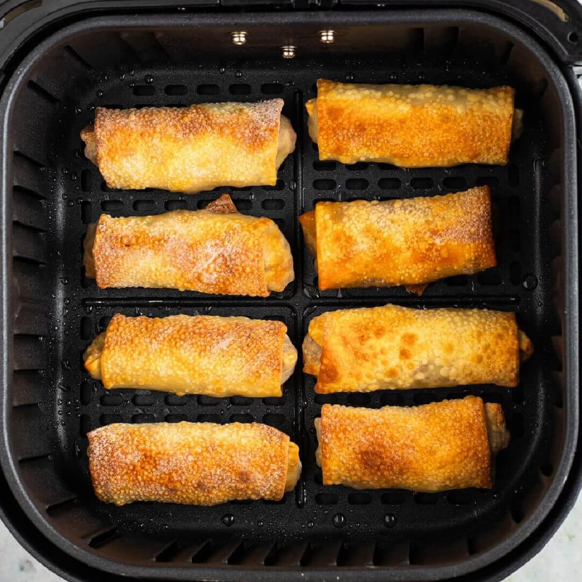 Egg rolls in the air fryer basket, fully cooked, and ready to serve.