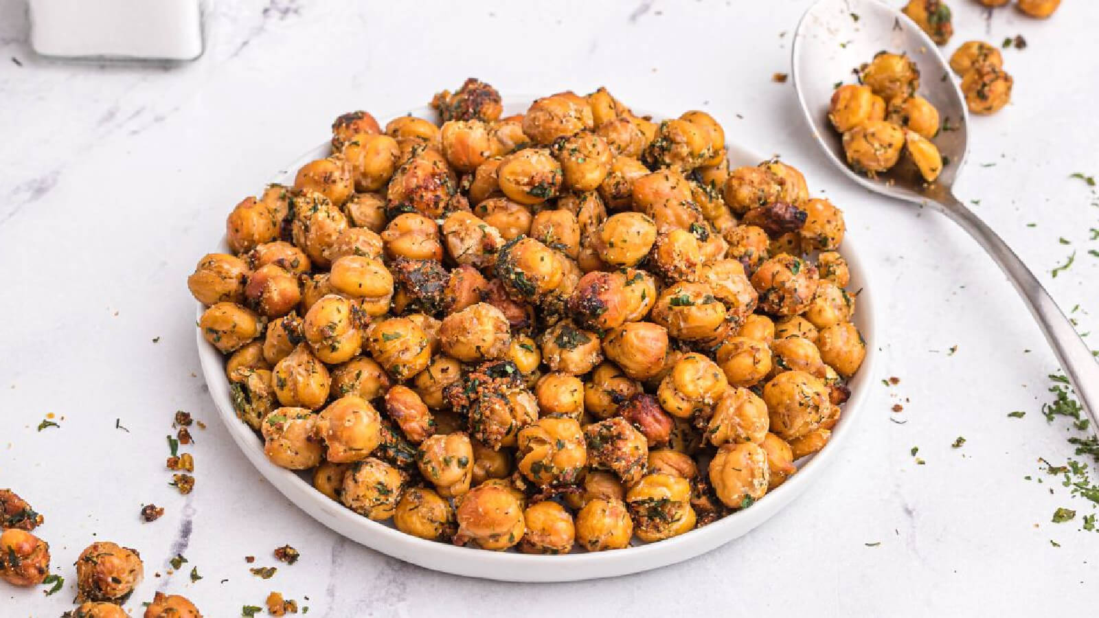 crispy chickpeas on a white plate with some on a spoon in the background.
