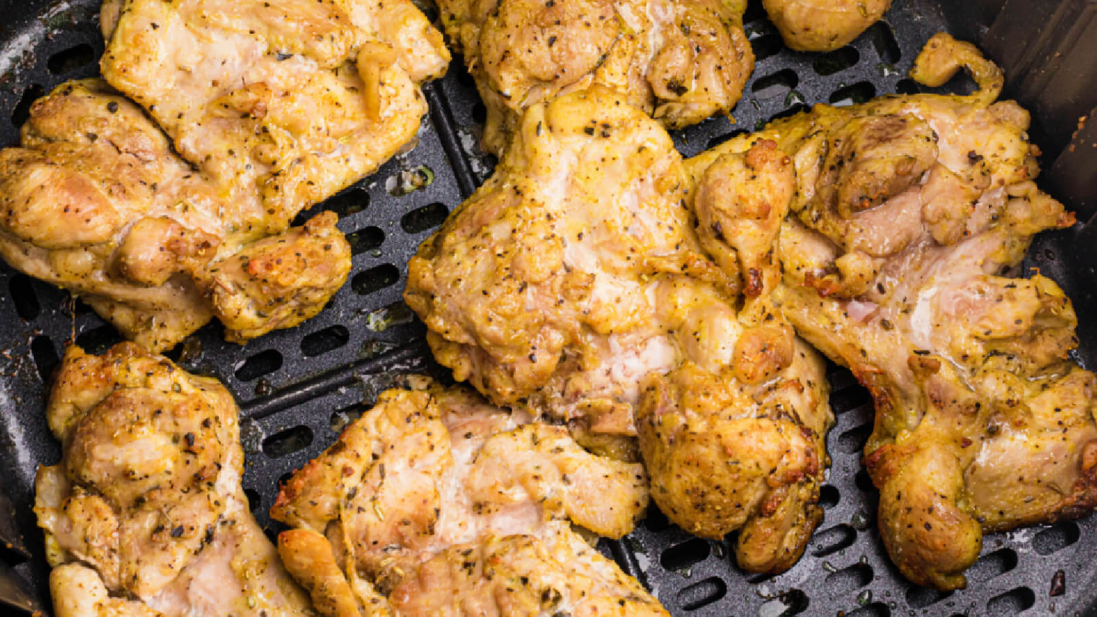 lemon pepper chicken thighs in the basket of the air fryer, ready to serve.