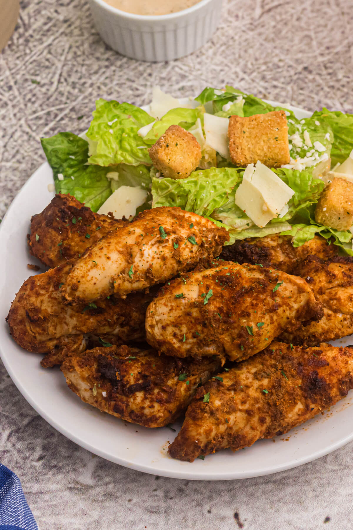 blackened chicken tenders on a plate with a salad.