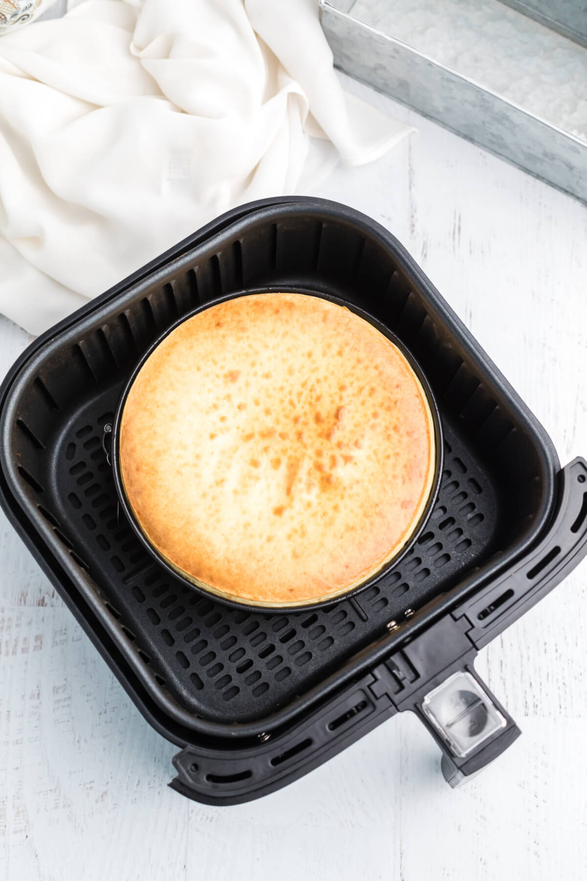 Fully cooked cheesecake in the basket of the air fryer, ready to be removed and chilled before serving. 