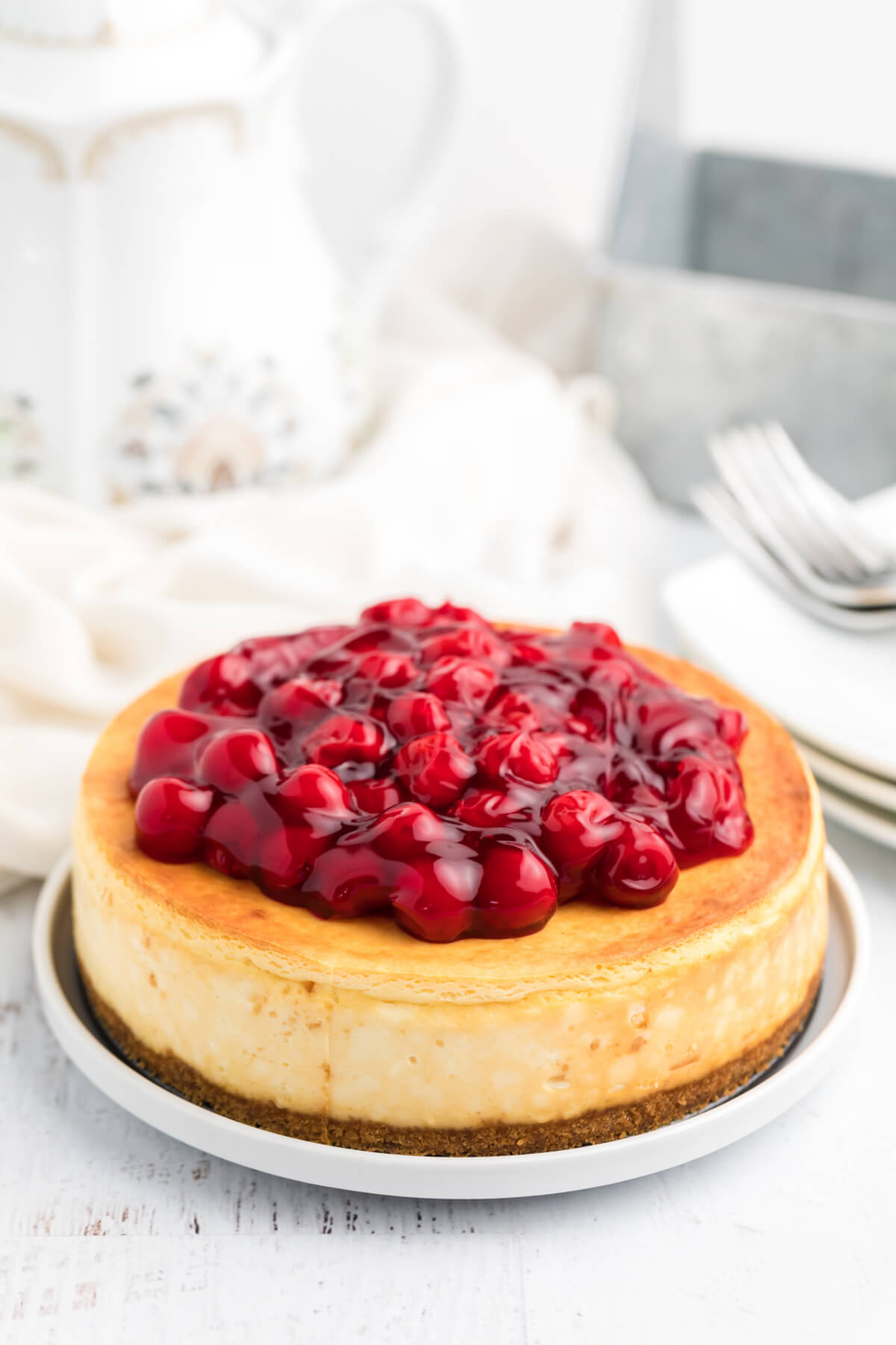 Cheesecake topped with cherries in front of an air fryer. 