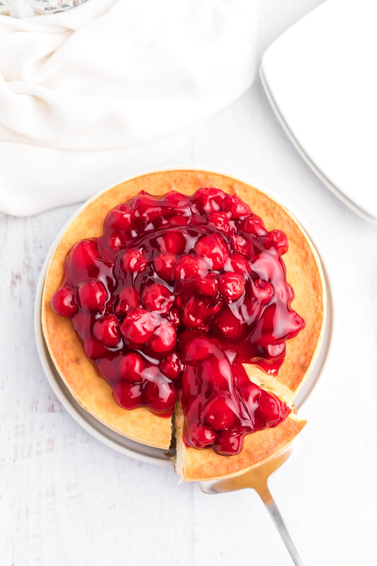 air fryer cheesecake with cherry topping sliced and being served. 