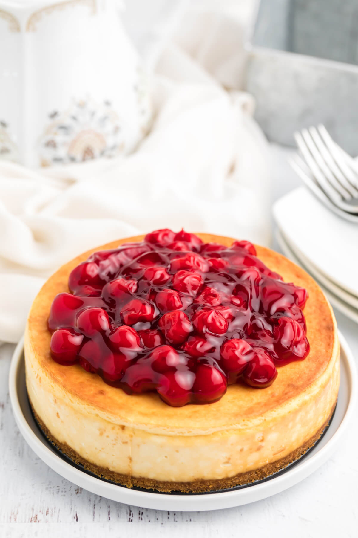 Cherry covered air fryer cheesecake served on a white plate. 