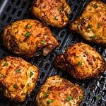 olden brown crispy chicken thighs in the air fryer basket after being cooked.