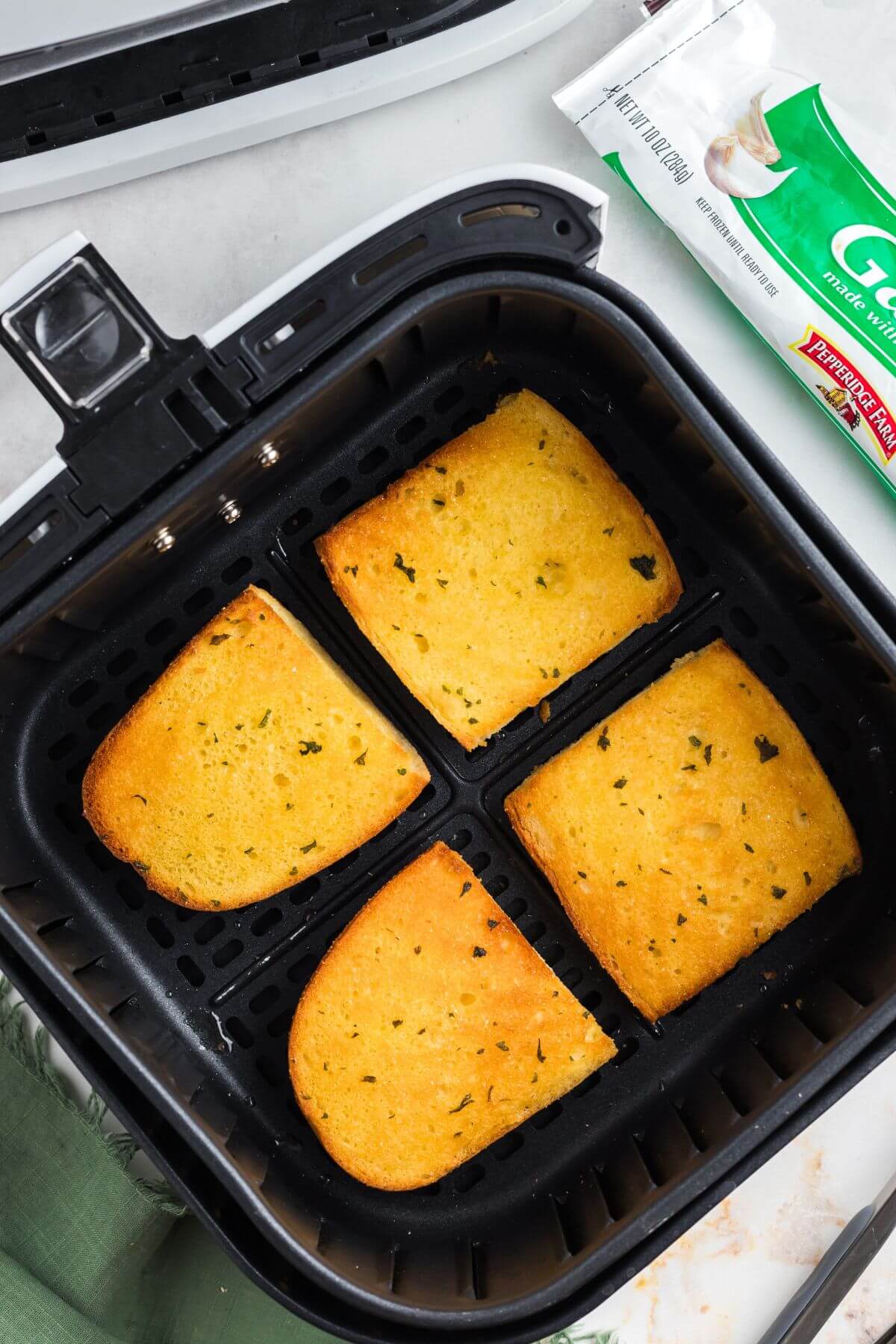 Golden crispy garlic bread slices in the air fryer basket after being cooked. 