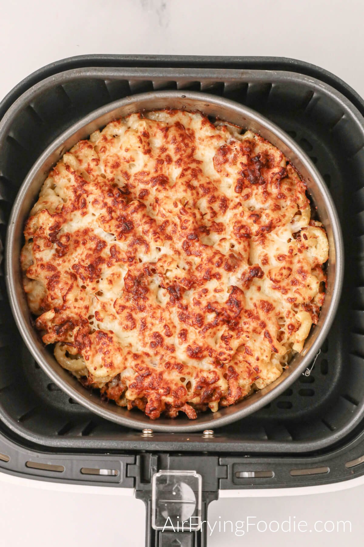 Air fried macaroni and cheese in a baking dish in the basket of the air fryer. 