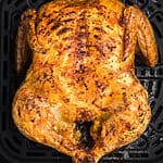 Whole chicken in air fryer basket, fully cooked and ready to remove, slice, and serve.