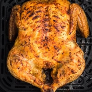 Whole chicken in air fryer basket, fully cooked and ready to remove, slice, and serve.