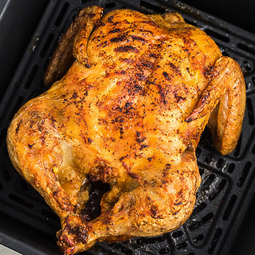 Rotisserie Chicken reheated in the air fryer, sitting in an air fryer basket, ready to be removed and served.
