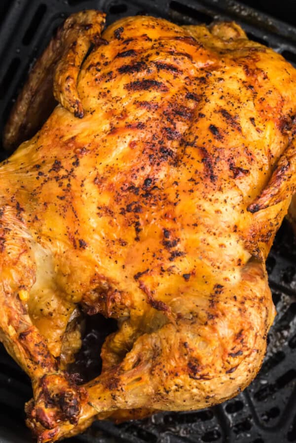 Rotisserie Chicken reheated in the air fryer, sitting in an air fryer basket, ready to be removed and served.