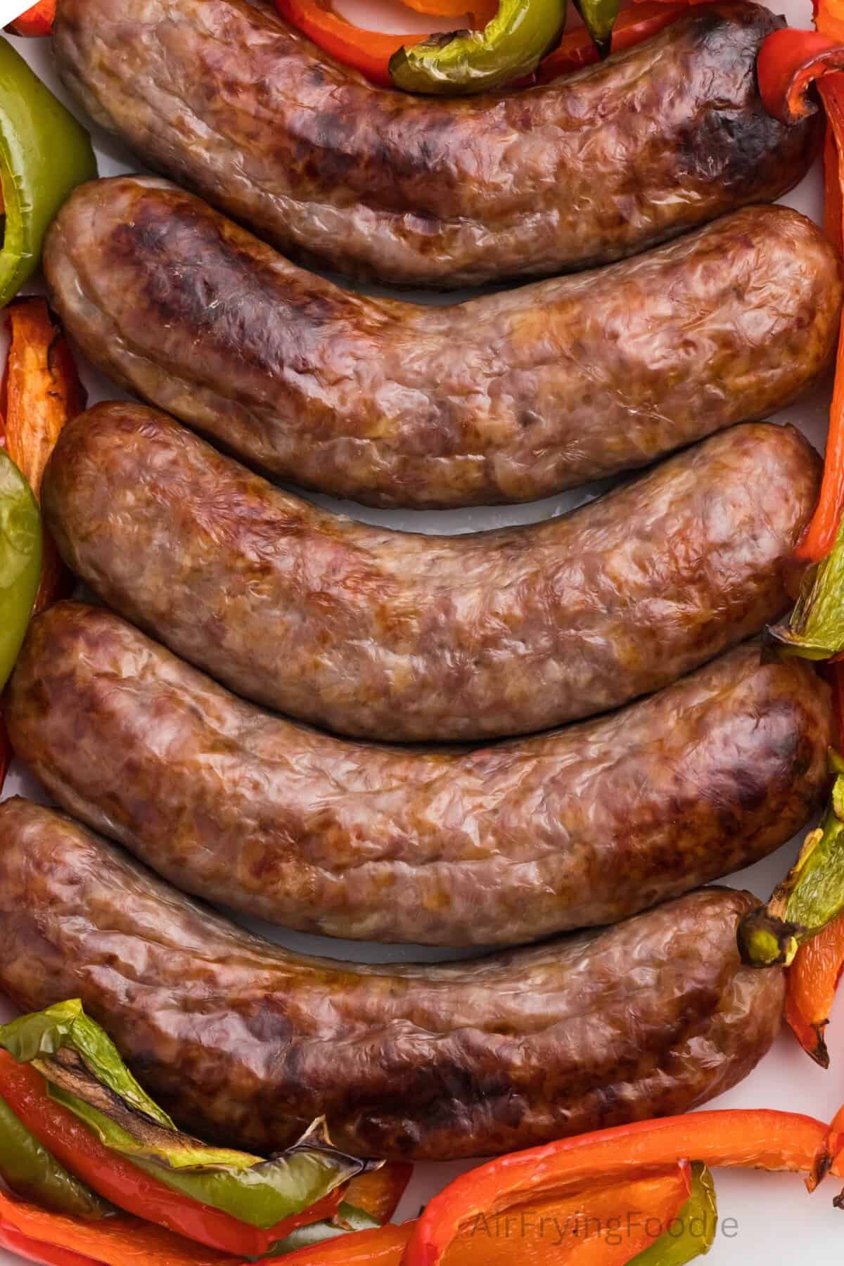 Air fried brats with peppers on a platter.