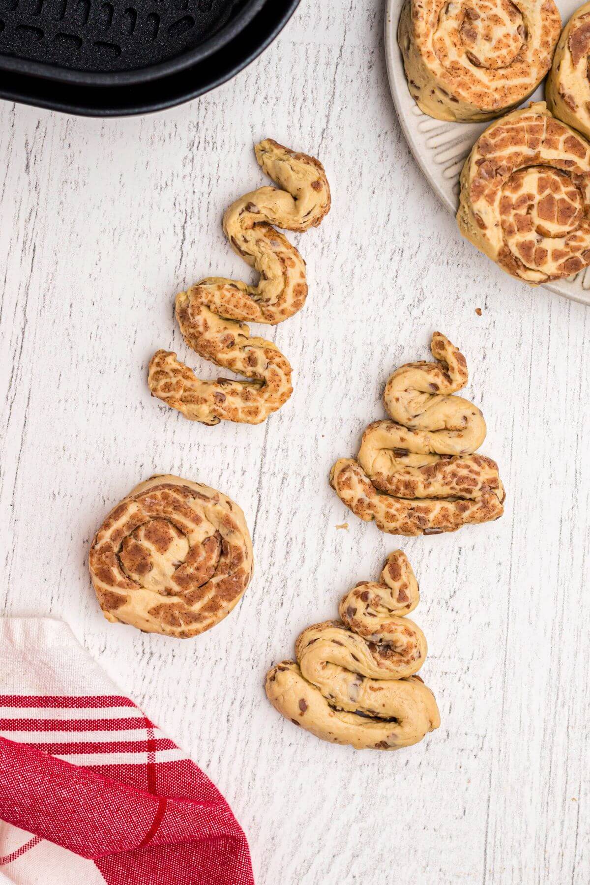 Uncooked cinnamon rolls, unrolled and reshaped into tree shapes. 