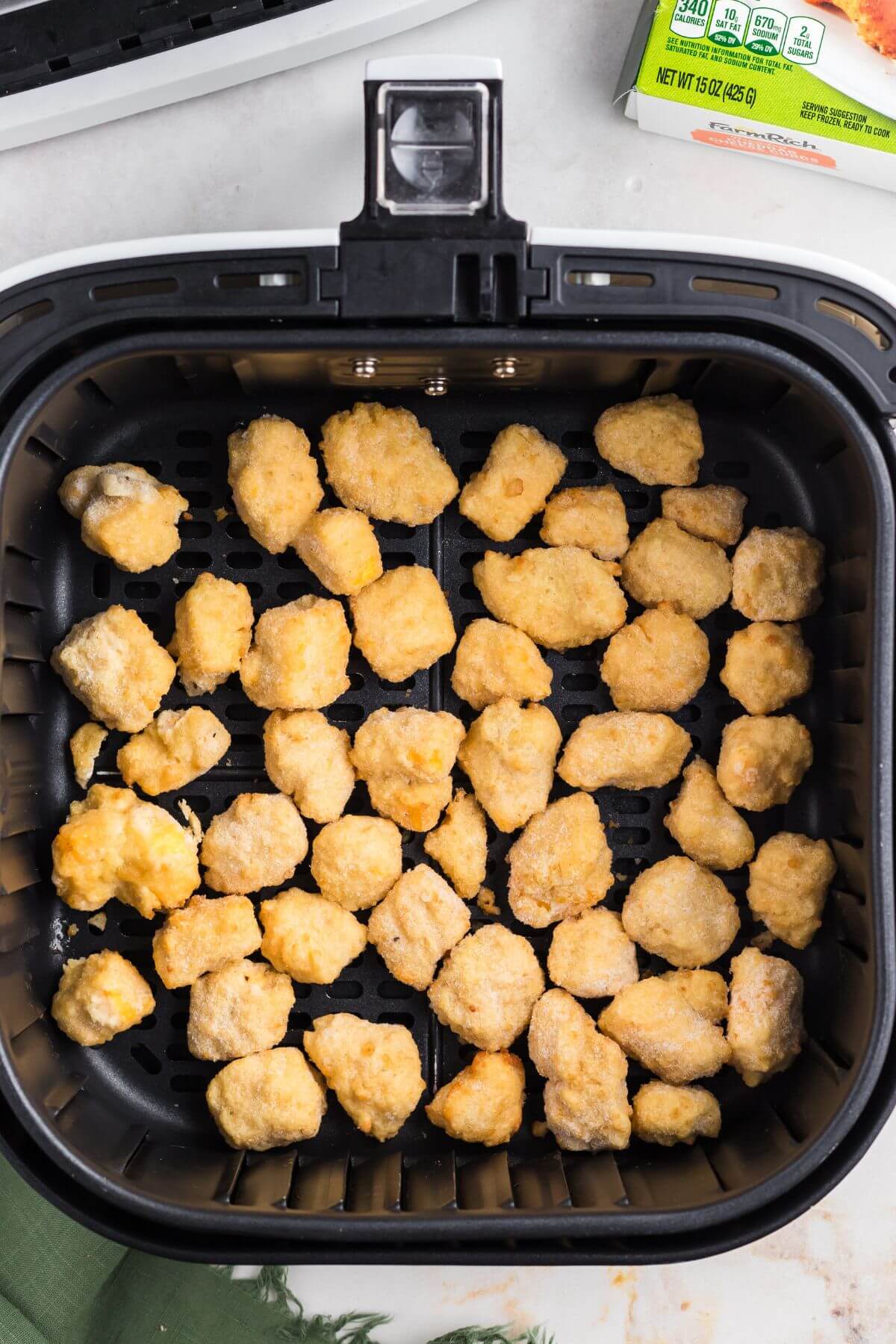 Frozen breaded cheese curds in the air fryer basket. 
