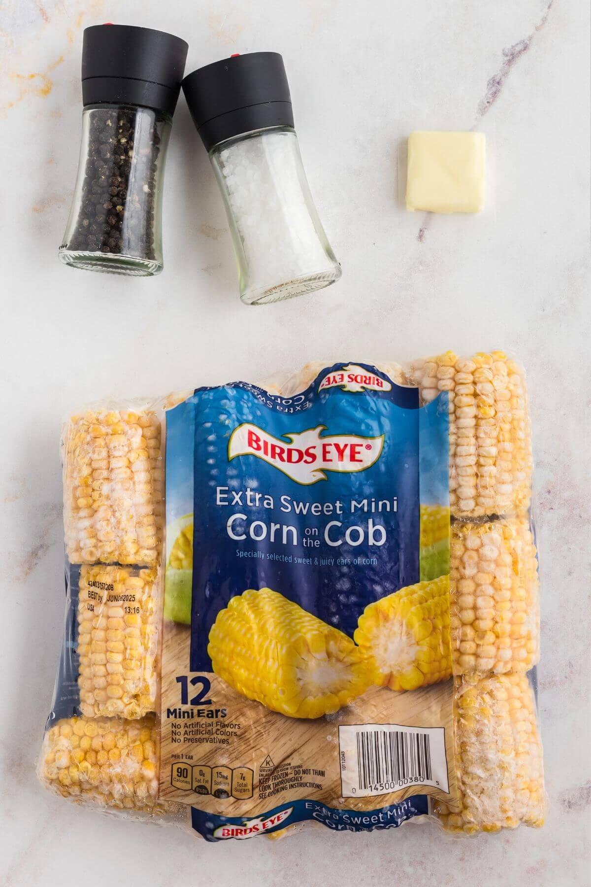 Frozen corn on the cob with salt and pepper shakers and a slab of butter. 