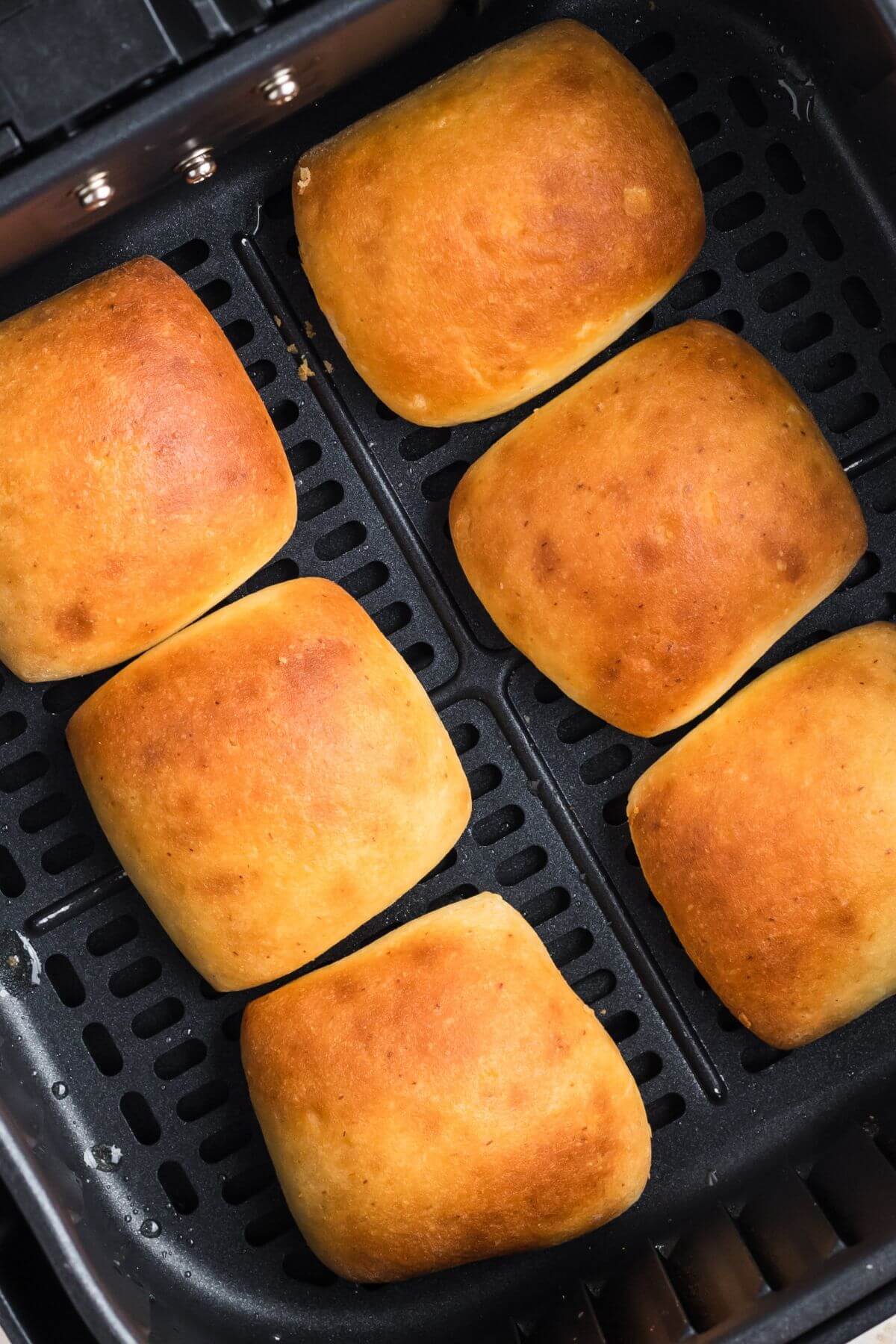 Golden brown cooked rolls in the air fryer basket. 