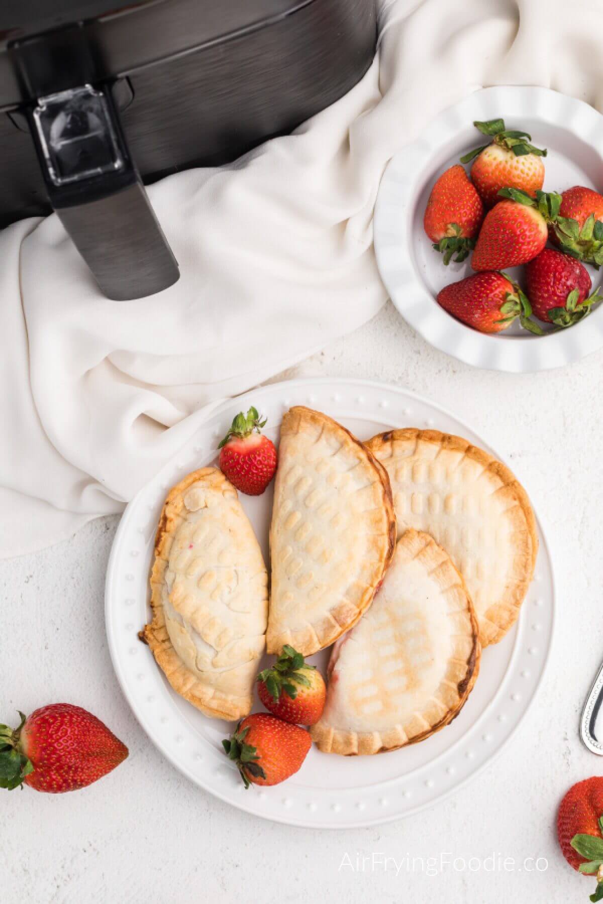Strawberry cream cheese hand pies made in the air fryer, and served on a white plate. 