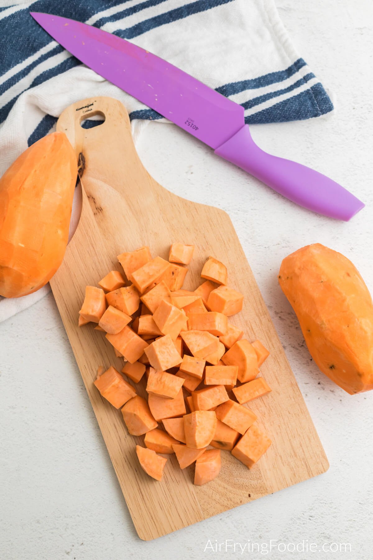 Sweet potato cut into small cubes on a cutting board. 