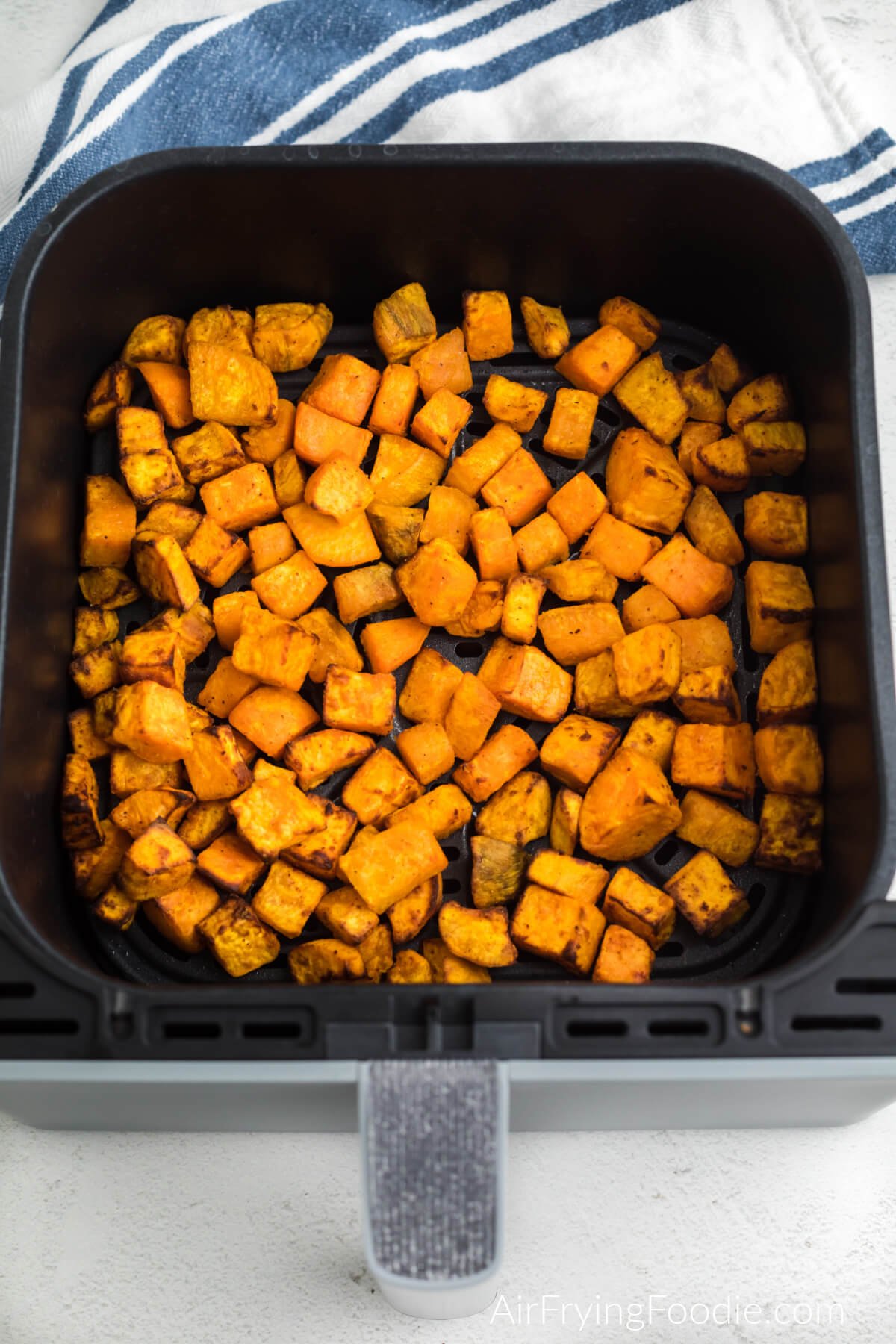 Air fried sweet potato cubes in the basket of the air fryer. 