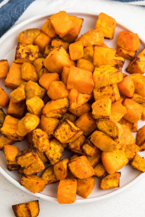 Overhead shot of air fryer sweet potato cubes on a white plate ready to serve.