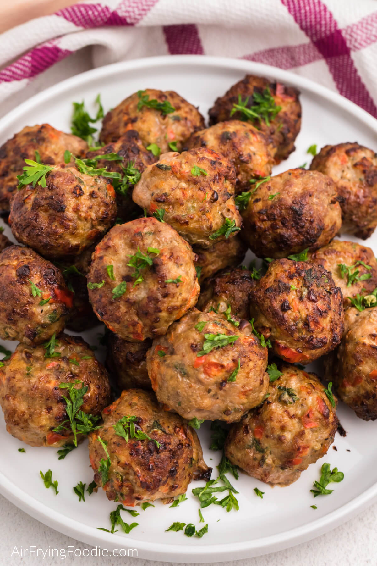 Air fryer turkey meatballs on a white plate with fresh parsley, ready to eat. 
